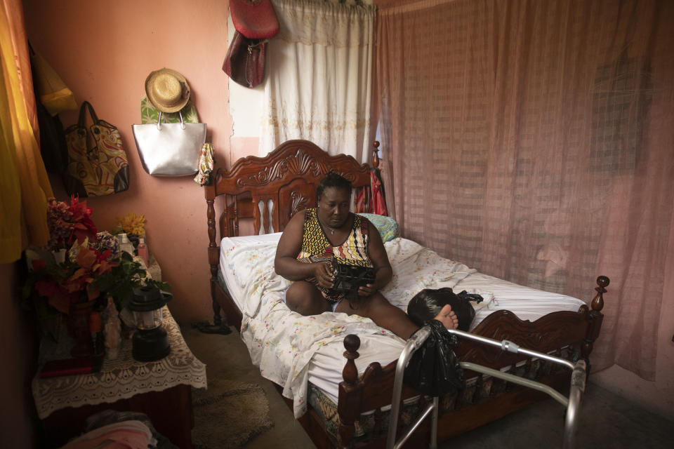 Duverseau Marie Cephta, whose leg was amputated when she was injured in last year's 7.2-magnitude earthquake, listens to news via a radio inside her home in the Lagodray area of Les Cayes, Haiti, Friday, Aug. 19, 2022. (AP Photo/Odelyn Joseph)