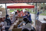 Non-governmental organization Resala Nour Ala Nour workers prepare cartons filled with food to distribute to people who have been greatly affected by the coronavirus outbreak, in Cairo, Egypt, Thursday, April 9, 2020. (AP Photo/Nariman El-Mofty)