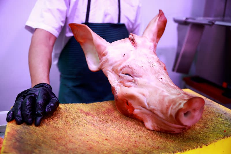 A butcher shows a pork's head at a market stall in Madrid