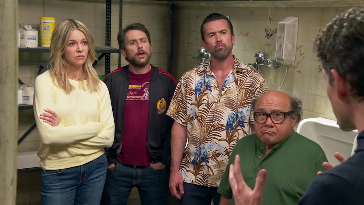  Dee (Kaitlin Olson), Charlie (Charlie Day), Mac (Rob McElhenney) and Frank (Danny DeVito) looking at Dennis (Glenn Howerton) almost off camera in a still from It's Always Sunny In Philadelphia season 15. 