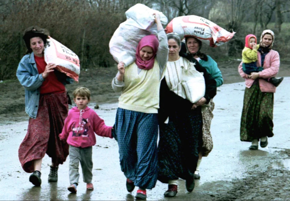 Bosnian refugees carry bags of relief aid near the besieged town of Srebrenica in 1993.