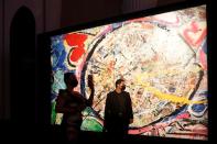 A visitor takes a photo as she walks past a painting by the British artist Sacha Jafri at the Atlantis hotel in Dubai