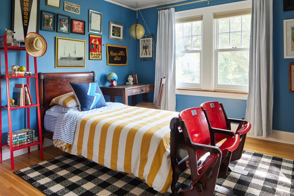 Boy's room painted blue with red vintage stadium seating at the foot of bed. 