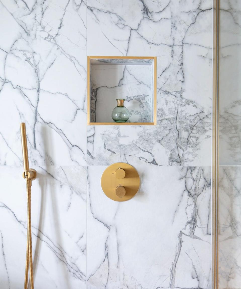 marble tiles in a shower with gold hardware