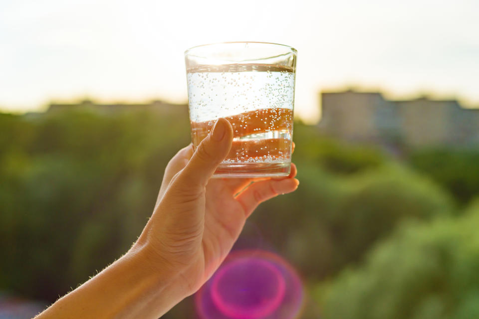 A hand holding a glass of sparkling water