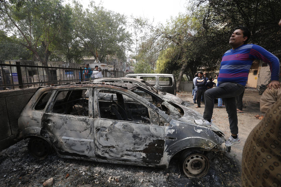 A man stands on a car vandalized in Tuesday's violence in New Delhi, India, Wednesday, Feb. 26, 2020. At least 20 people were killed in three days of clashes in New Delhi, with the death toll expected to rise as hospitals were overflowed with dozens of injured people, authorities said Wednesday. The clashes between Hindu mobs and Muslims protesting a contentious new citizenship law that fast-tracks naturalization for foreign-born religious minorities of all major faiths in South Asia except Islam escalated Tuesday. (AP Photo/Rajesh Kumar Singh)