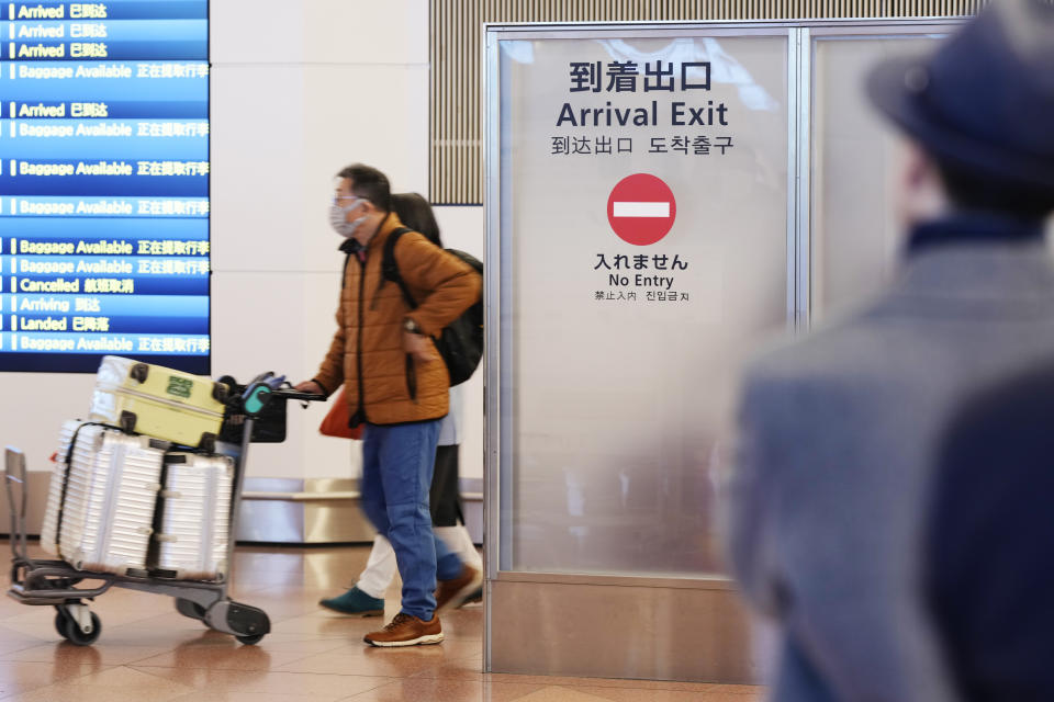 Airplane passengers go through a gate after they arrived at a terminal for international flights at the Haneda International Airport in Tokyo, Saturday, Jan. 14, 2023. A hoped-for boom in Chinese tourism in Asia over next week’s Lunar New Year holidays looks set to be more of a blip as most travelers opt to stay inside China if they go anywhere. (AP Photo/Hiro Komae)