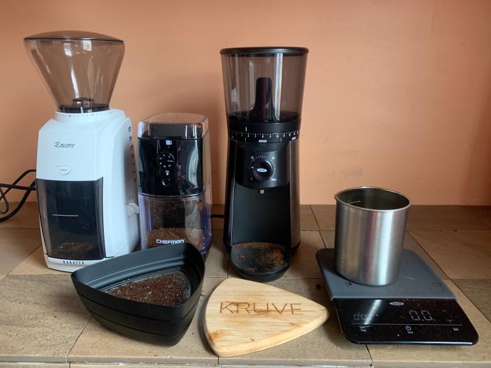 Three of the coffee grinders we've tested with a Kruve coffee sifter and a kitchen scale to determine consistency