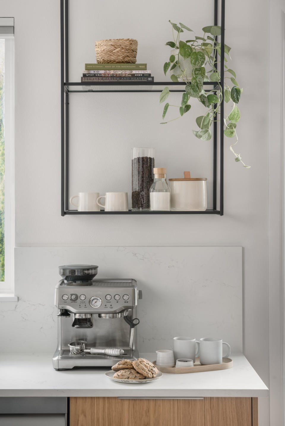 A silver coffee maker beneath metal shelving