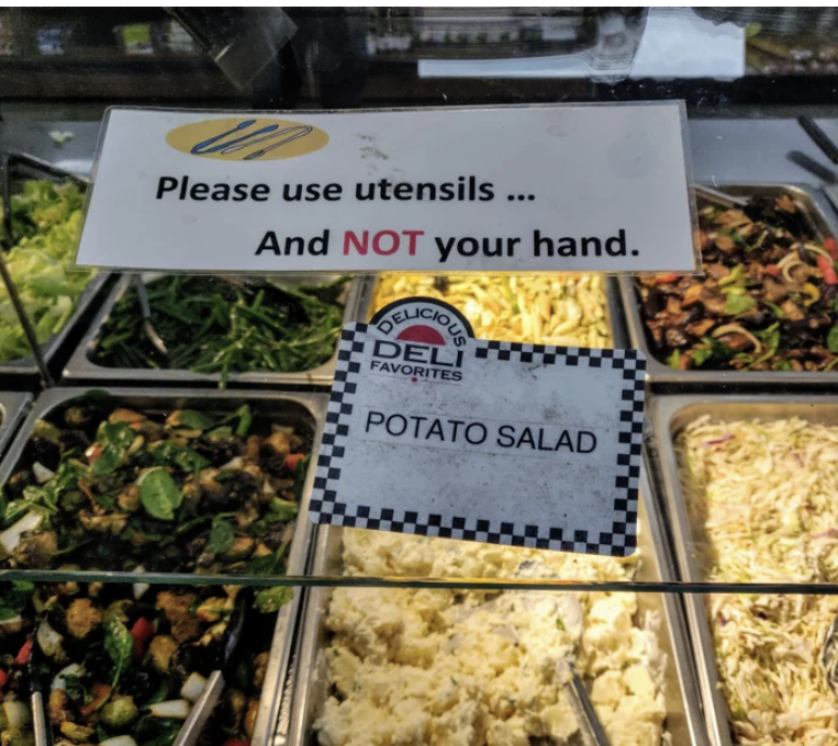 A buffet features a sign next to the potato salad that says "please use utensils and not your hand"