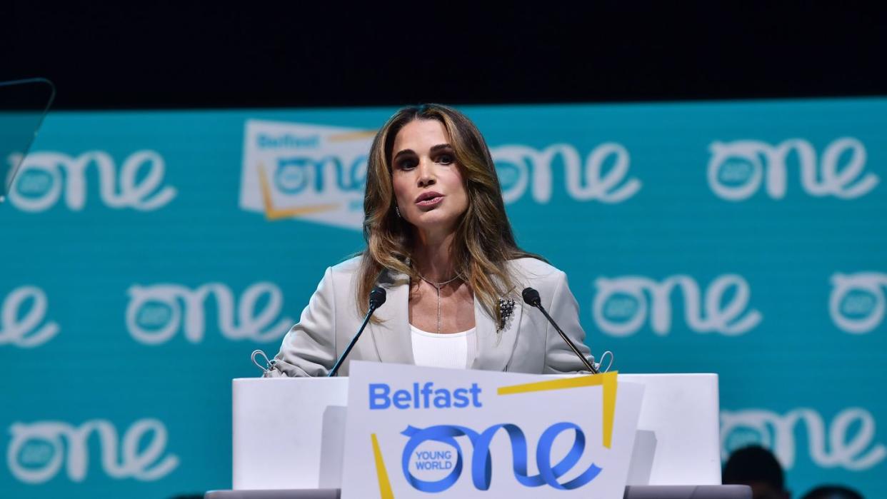 queen rania speaking to an audience from a podium with microphones