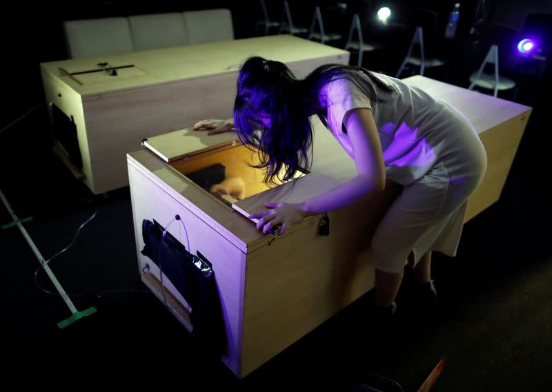 An actor dressed as zombie performs during a coffin horror show for participants to lie inside a mock of coffin with a plastic shield in order to maintain social distancing amid the spread of the coronavirus disease (COVID