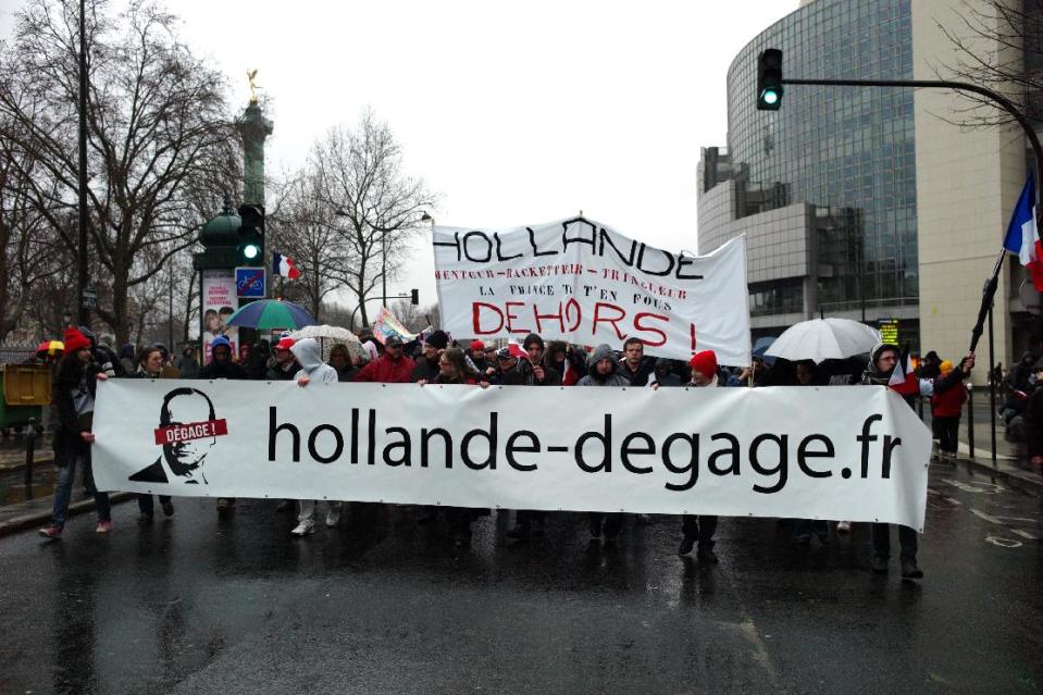 Protesters hold a banner reading "Hollande Get Out" during a demonstration criticizing President Francois Hollande, in Paris, Sunday Jan. 26, 2014. Carrying banners saying "The French are angry!" Sunday's demonstration by people from about 50 organizations cited France's struggling economy and high unemployment, its taxes, their housing needs and lack of personal freedoms. (AP Photo/Thibault Camus)