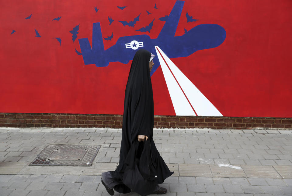 A woman walks past a new anti-U.S. mural on the wall of former U.S. embassy portraying the interception of Global Hawk US drone by Iran in Persian Gulf, after an unveiling ceremony in Tehran, Iran, Saturday, Nov. 2, 2019. Anti-U.S. works of graphics is the main theme of the wall murals painted by a team of artists ahead of the 40th anniversary of the takeover of the U.S. diplomatic post by revolutionary students. (AP Photo/Vahid Salemi)