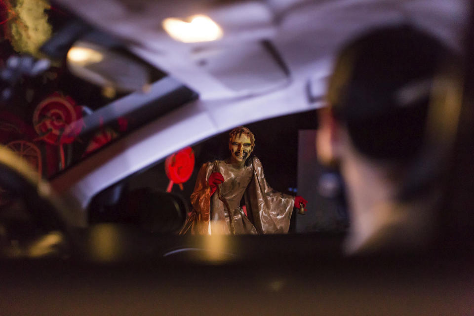 An actor dressed as a witch performs at the Hopi Hari horror theme amusement park, in the Vinhedo suburb of Sao Paulo, Brazil, Friday, Sept. 4, 2020. Due to the restrictions caused by COVID-19, the park created a drive-thru tour that allow the public to enjoy the experience by car. (AP Photo/Carla Carniel)