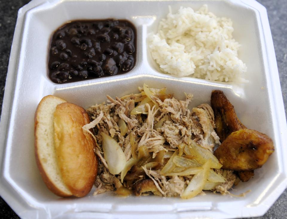 A serving of lechon asado or roasted pork with black beans and rice is served at the Love at First Bite by A Taste of Cuba food truck on Friday, Nov. 17, 2023.