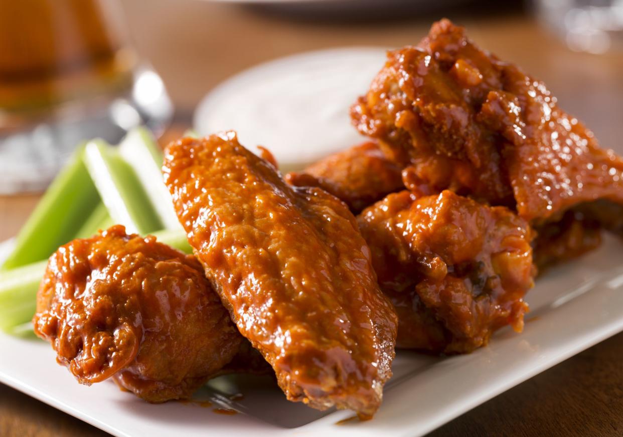 A plate of buffalo style chicken wings with celery and blue cheese with a beer on a bar or restaurant table.  Please see my portfolio for other food and drink images.