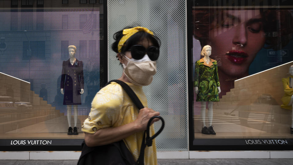 A woman wearing a mask walks by a Louis Vuitton store, Thursday, June 11, 2020, in New York's Fifth Avenue shopping district. The luxury goods store is open for curbside pickup. The New York City immortalized in song and scene has been swapped out for the last few months with the virus version. In all the unknowing of what the future holds, there’s faith in that other quintessential facet of New York City: that the city will adapt. (AP Photo/Mark Lennihan)