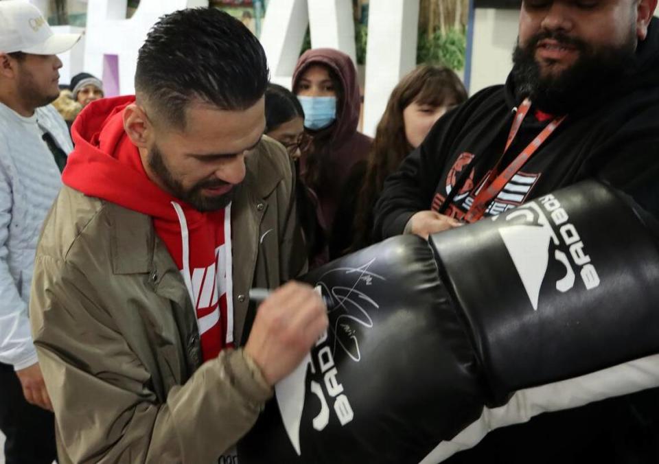 José Ramírez signs an oversized boxing glove during a visit to the Boys & Girls Club in central Fresno on March 22. He will face Richard Commey in a 12-round junior welterweight WBC title eliminator bout March 25 at the Save Mart Center.