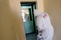 A man wearing a protective suit sanitizes the elevator of a public housing building to prevent the spreading of the coronavirus, in the neighborhood of Spinaceto, on the outskirts of Rome, Monday, March 30, 2020. The new coronavirus causes mild or moderate symptoms for most people, but for some, especially older adults and people with existing health problems, it can cause more severe illness or death. (Mauro Scrobogna/LaPresse via AP)