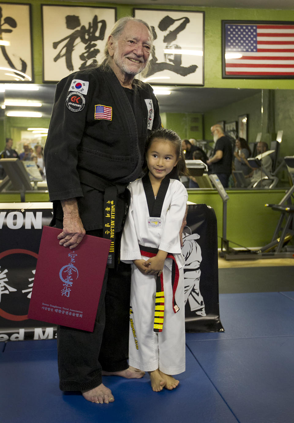 Willie Nelson, the country music icon who turns 81 this week, poses with Reese Park, 5, one of the youngest pupils of Sam Um, as he receives his fifth-degree black belt in the martial art of Gong Kwon Yu Sul on Monday, April 28, 2014, in Austin, Texas. (AP Photo/Austin American-Statesman, Ralph Barrera) AUSTIN CHRONICLE OUT, COMMUNITY IMPACT OUT, INTERNET AND TV MUST CREDIT PHOTOGRAPHER AND STATESMAN.COM, MAGS OUT