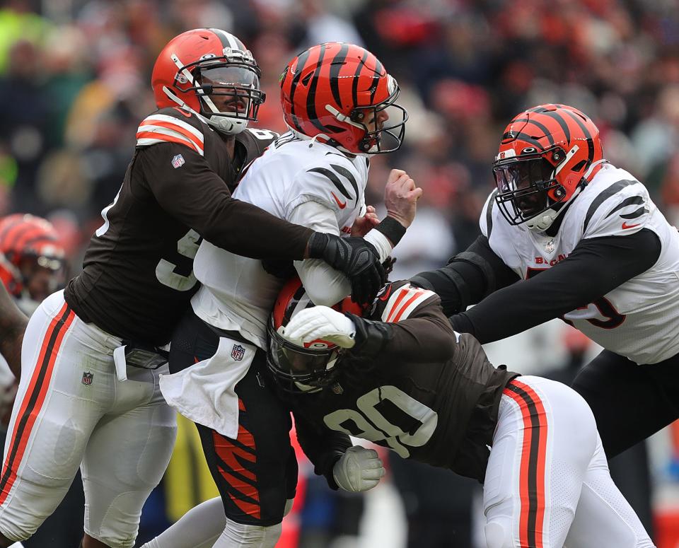 Cleveland Browns defensive end Myles Garrett (95) and Cleveland Browns defensive end Jadeveon Clowney (90) sandwich Cincinnati Bengals quarterback Brandon Allen (8) during the first half of an NFL football game, Sunday, Jan. 9, 2022, in Cleveland, Ohio. [Jeff Lange/Beacon Journal]