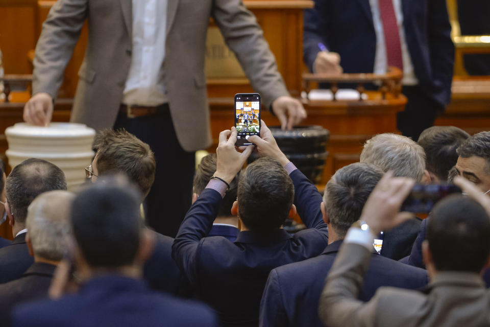 Members of parliament take pictures during a parliament vote on Romanian Prime Minister designate Nicolae Ciuca and his government team in Bucharest, Romania, Thursday, Nov. 25, 2021. Romanian lawmakers voted in favor of a new coalition government led by a Liberal former army general, which could usher in an end to a months-long political crisis in the Eastern European nation.(AP Photo/Alexandru Dobre)