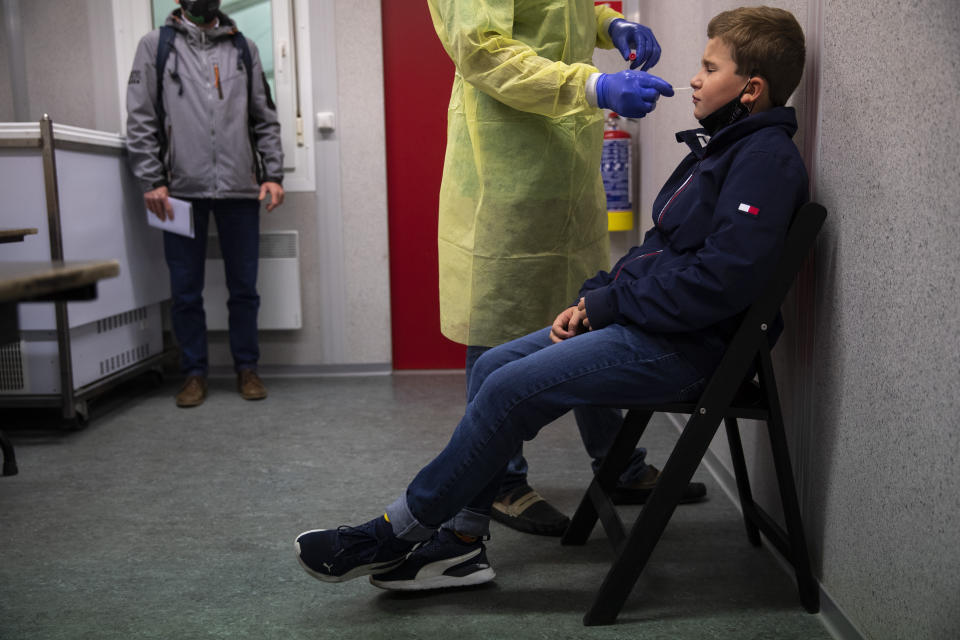 A medical worker, wearing full protective gear, takes a nose swab from a patient to be tested for COVID-19 in a Red Cross test center in Brussels, Tuesday, Oct. 20, 2020. Bars and restaurants across Belgium shut down for a month and a night-time curfew entered into force Monday in the hard-hit coronavirus country as health authorities warned of a possible sanitary “tsunami." (AP Photo/Francisco Seco)