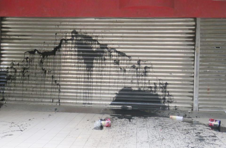 慶平路一家汽車美容店的鐵捲門遭潑黑漆。（記者陳治交攝）
