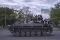 Ukrainian serviceman wave a flag with writing reading in Ukrainian "Glory to Ukraine", top, and "Death to the enemies" as they ride atop of a tank in the Kharkiv region, eastern Ukraine, Monday, May 16, 2022. (AP Photo/Bernat Armangue)