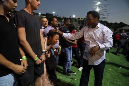 A woman reacts as her head touched by T.B. Joshua, a Nigerian evangelical preacher as he leads a religious retreat on Mount Precipice, Nazareth