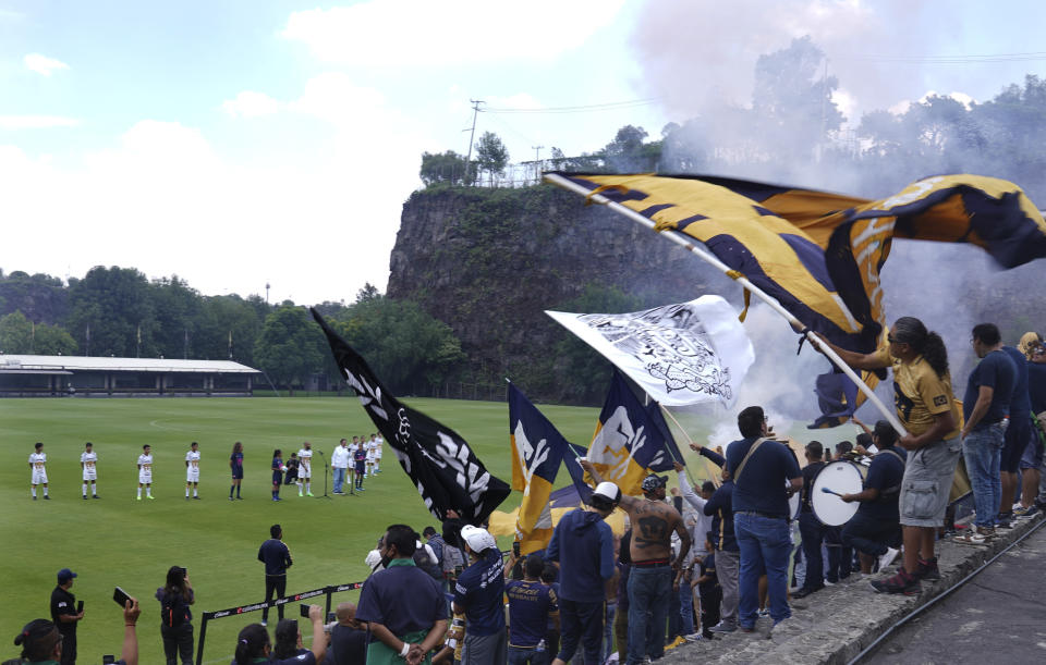 Fans wave team banners during a presentation of Brazilian Dani Alves, a new member of the Pumas UNAM soccer club, at the Pumas training facility in Mexico City, Saturday, July 23, 2022. (AP Photo/Marco Ugarte)