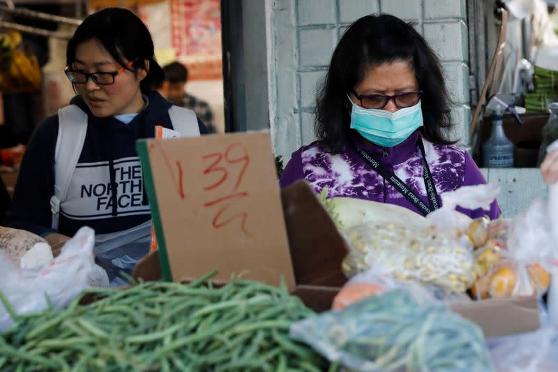 A woman wears a face mask shopping at a market in the Chinatown section of San Francisco, California