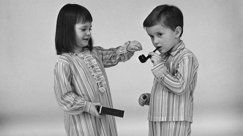 Black and white photo of two children smoking pipe