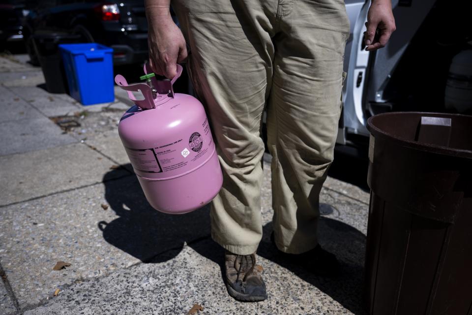 Jennifer Byrne, owner and technician at Comfy Heating and Cooling, pulls a tank of refrigerant from the work truck in Philadelphia on Thursday, Sept. 14, 2023. Refrigerants are chemical fluids that have made air conditioning and refrigeration possible, but they are hundreds or even thousands of times more powerful at warming the planet than carbon dioxide, the most notorious greenhouse gas. (AP Photo/Joe Lamberti)