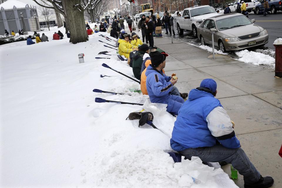 Workers take a lunch break from shoveling snow near the Statehouse in Tuesday, Feb. 18, 2014, in Trenton, N.J., after a quick-moving storm brought several inches of snow as well as rare "thundersnow" to parts of the winter-weary East Coast. (AP Photo/Mel Evans)