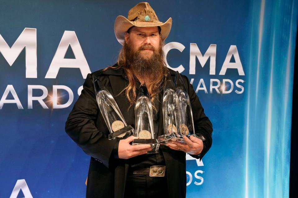 Chris Stapleton poses in the press room with the awards for entertainer of the year, male vocalist of the year, and album of the year.