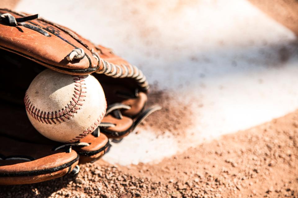 A baseball glove and ball are shown at home plate.