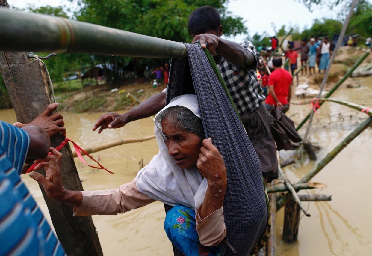 A Rohingya refugee woman is carried in a sling, through a swollen water stream in Cox's Bazar, Bangladesh: Reuters