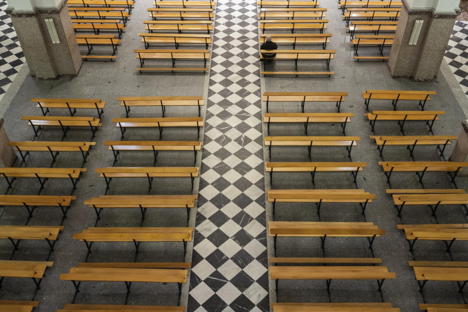 A Catholic priest sits on an empty bench due to social distancing guidelines during the coronavirus outbreak inside the Jesus de Medinaceli church on Palm Sunday in Madrid, Spain, Sunday, April 5, 2020. The new coronavirus causes mild or moderate symptoms for most people, but for some, especially older adults and people with existing health problems, it can cause more severe illness or death. (AP Photo/Bernat Armangue)