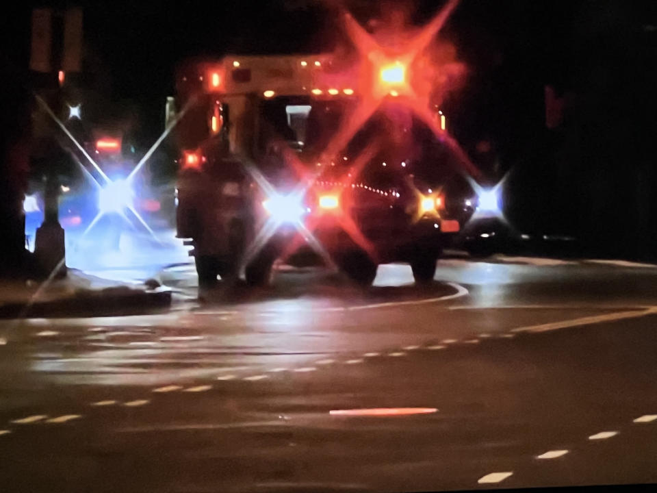 An emergency vehicle with flashing lights navigates through an intersection at night