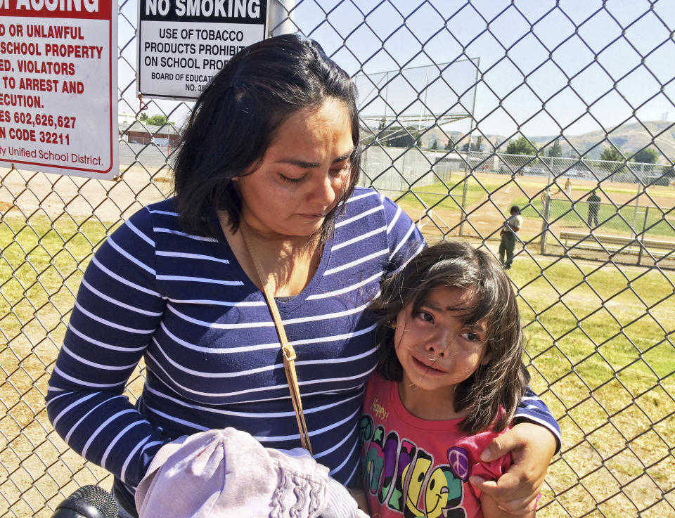 Elizabeth Barajas abraza a su hija, Marissa Pérez, de 9 años, después de que Marissa atestiguó cómo un hombre armado ingresó a su salón en la escuela primaria North Park y mató a su maestra antes de suicidarse, el lunes 10 de abril de 2017 en San Bernardino, California. (AP Foto/Christopher Weber)