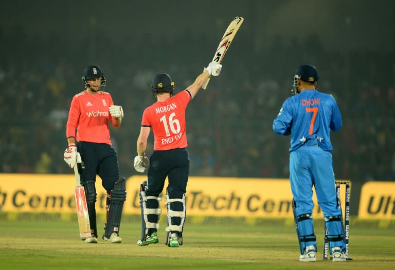 England captain Eoin Morgan (C) raises his bat after completing his half century (50 runs) during the first T20 match against India at Green Park Stadium in Kanpur, central India, on January 26, 2017