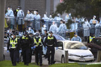 Police officers and healthcare workers are stationed outside a public housing tower that is locked down as a Coronavirus hotspot in Melbourne, Australia, Wednesday, July 8, 2020. Australian Prime Minister Scott Morrison says a shutdown of the nation's second-largest city is necessary and promised continuing financial support for businesses that fear they won't survive a second lockdown. (James Ross/AAP Image via AP)
