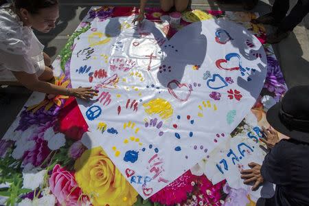 People leave messages on a banner for victims killed in Monday's bomb blast during a religious ceremony near at the Erawan shrine, the site of Monday's deadly blast, in central Bangkok, Thailand, August 21, 2015. REUTERS/Athit Perawongmetha