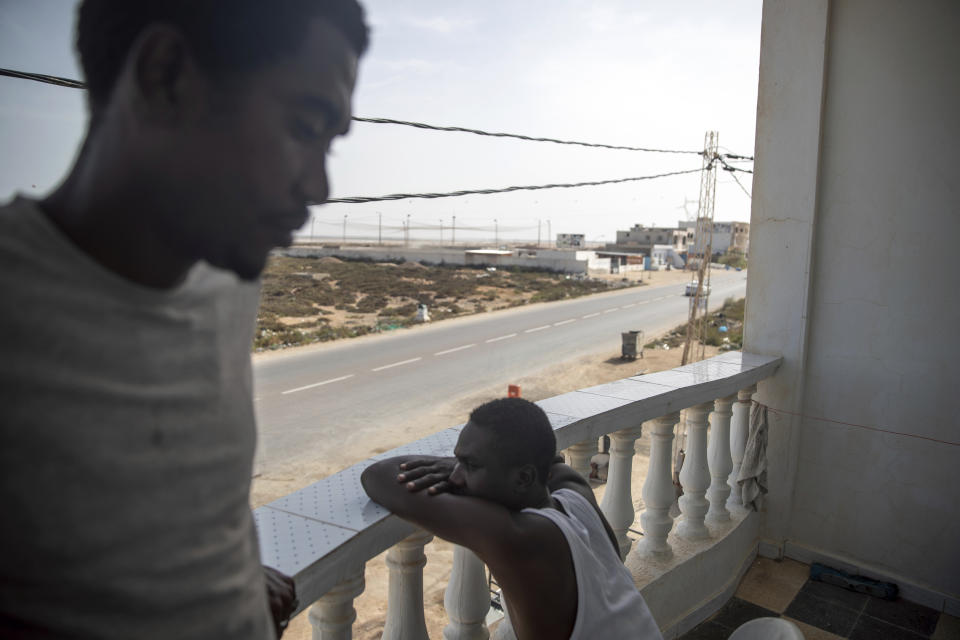 In this Monday, Sept. 23, 2019 photo, Sudanese migrants who tried crossing the Mediterranean from Libya sit in a balcony in a Tunisian Red Crescent facility in Zarzis, south of Tunisia. Tunisia offers an opportunity for militia networks to make money off European funds earmarked for migrants. Because of Libya’s dysfunctional banking system, international organizations give contracts, usually in dollars, to Libyan groups with bank accounts in Tunisia. These groups then pocket the money they make on the black-market exchange, which ranged between 4 and 9 times greater than the official rate. (AP Photo/Mosa'ab Elshamy)