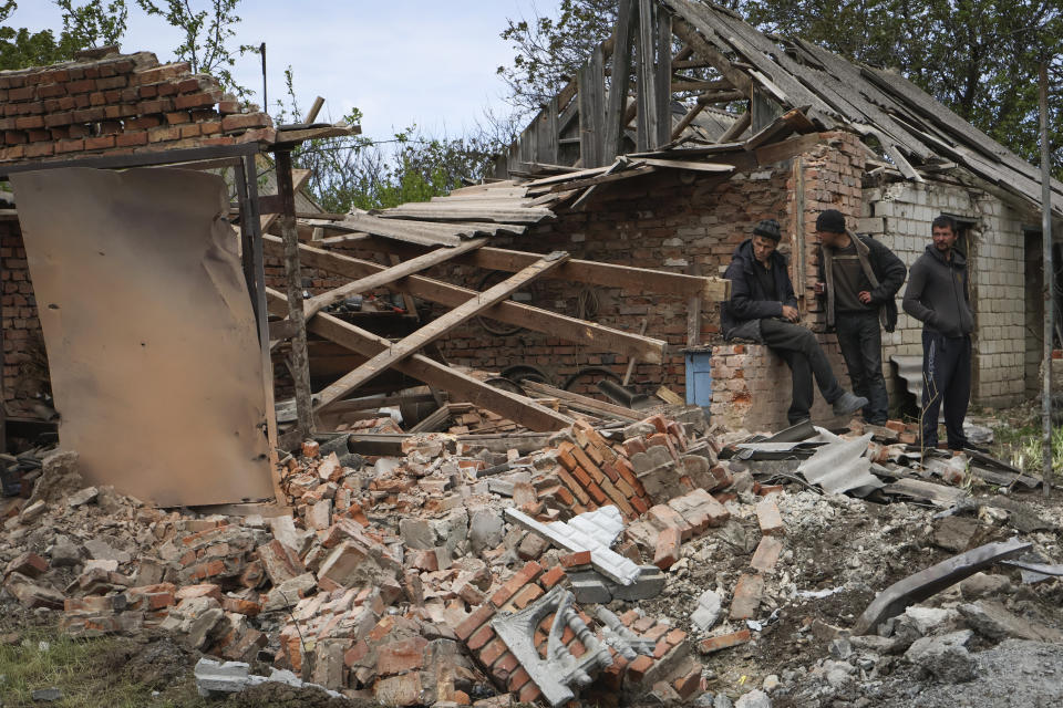 Local residents stand next to a building that was damaged in the night, following Russian shelling in Komyshevakha, Zaporizhzhia region, Ukraine, Monday, May 8, 2023. (AP Photo/Andriy Andriyenko)