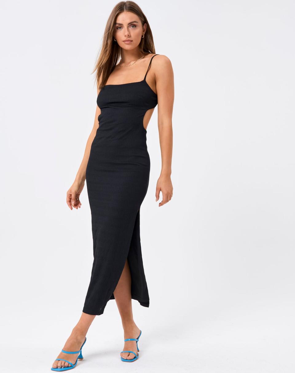 A model with long dark hair worn loose wears a black Backless Textured Stripe Side Split Maxi Dress with blue strappy high heels.