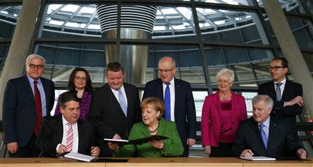 Party leaders German Chancellor Angela Merkel (C) of the Christian Democratic Union (CDU), Horst Seehofer (R) of the Christian Social Union (CSU) and Sigmar Gabriel of the Social Democratic Party (SPD) sign a preliminary agreement, which has still to be approved by the members of the SPD, in the Bundestag in Berlin, November 27, 2013. REUTERS/Tobias Schwarz