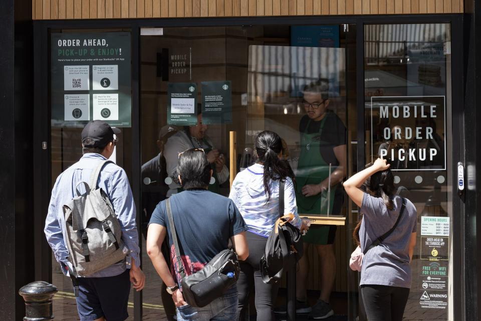 people queue outside a starbucks coffee house during the